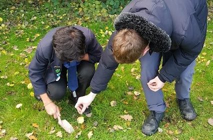 Two students planting seeds against a greenery background