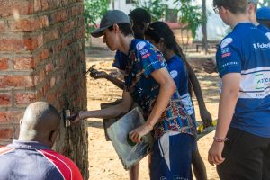 Volunteers working together to plaster or repair a brick wall as part of a community project.